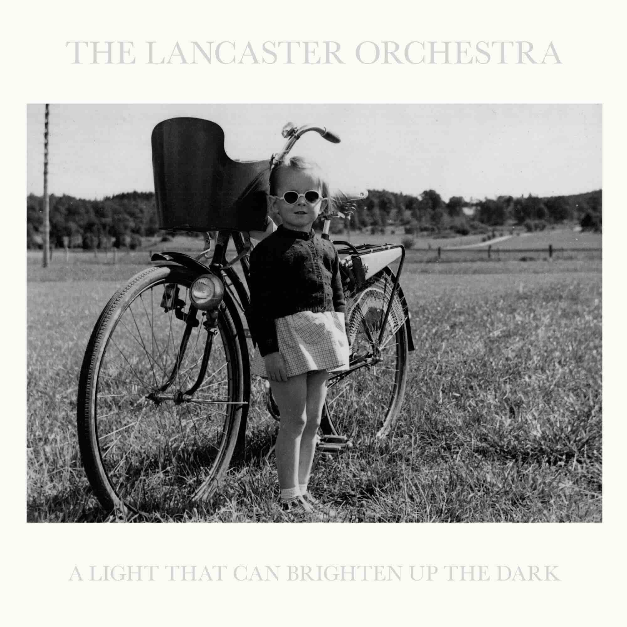 Cover art for the album - black and white photo of a girl about 4 years old with sunglasses standing in front of a bicycle.
